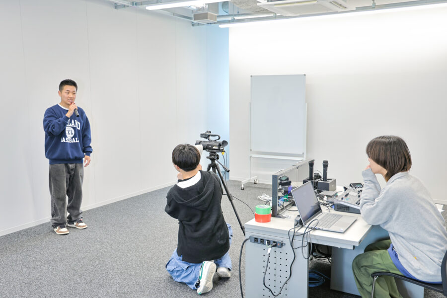 学生とカメラマンがバーチャル・スタジオを利用している敬愛大学稲毛キャンパス新1号館