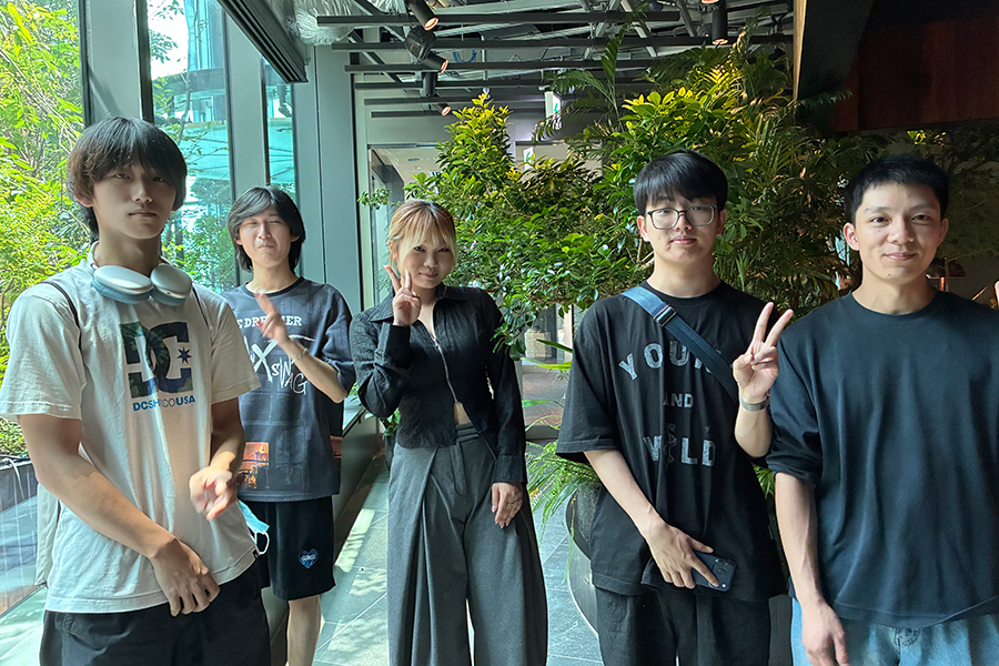 高輪ゲートウェイ駅周辺の屋内植栽スペースで、敬愛大学国際学部2年庄司ゼミの学生5人が並ぶ。SDGsの視点から、街の技術、環境、人への配慮を多面的に検証した現地調査の一場面。