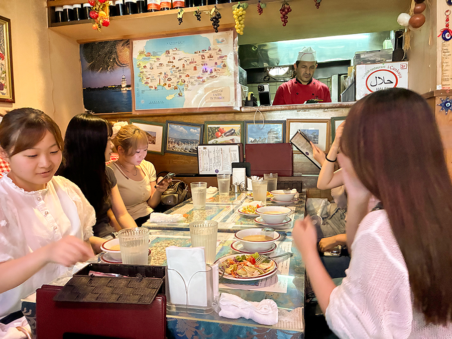新宿のトルコ料理店「チャンカヤ」で、ケバブ料理などを囲む敬愛大学国際学部1年庄司ゼミの学生。ハラル表示のある店内で、トルコの食文化と宗教のつながりを体験している。